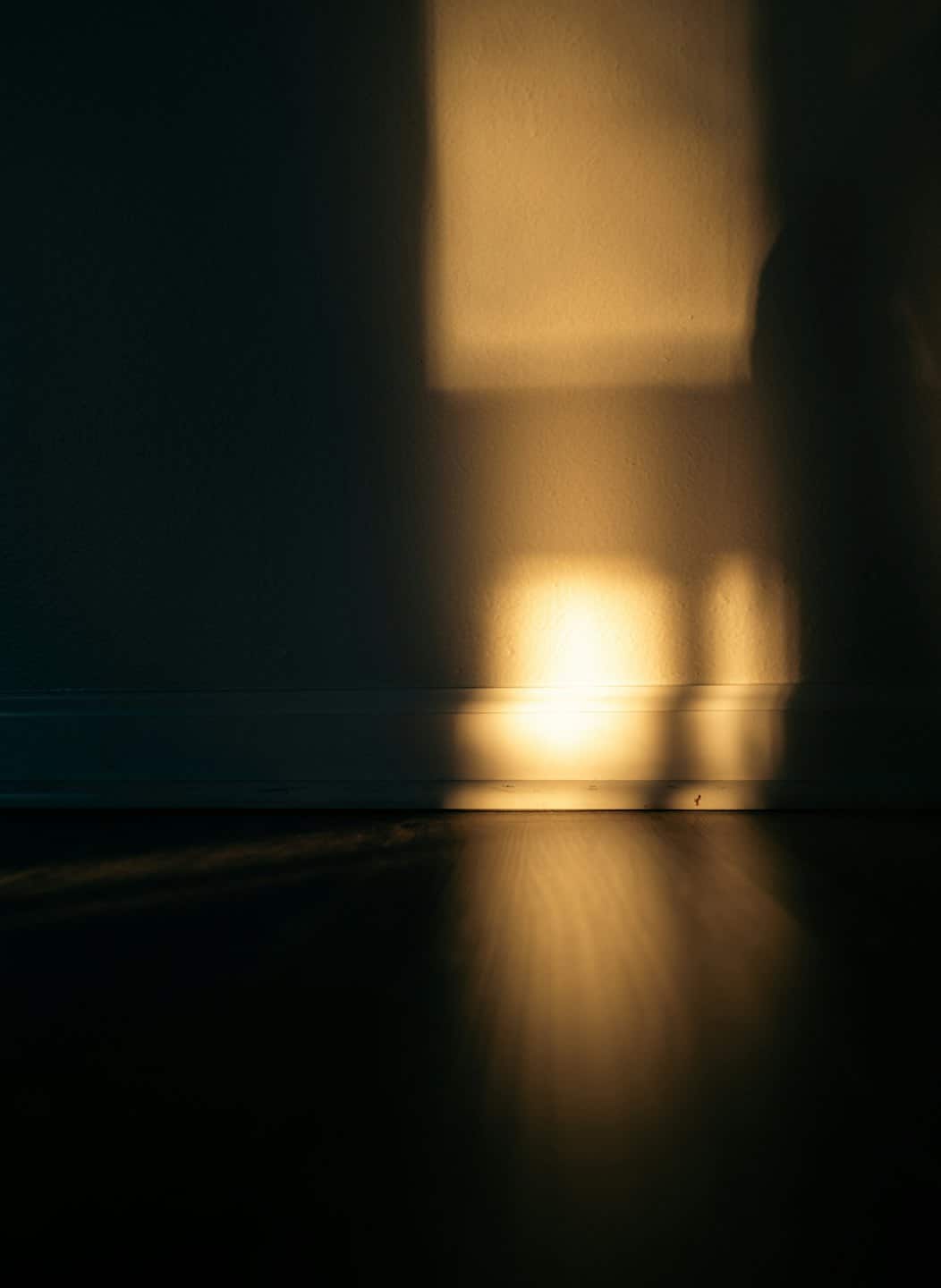 Sonnenlicht wirft rechteckige Muster auf Holzboden und -wand.
