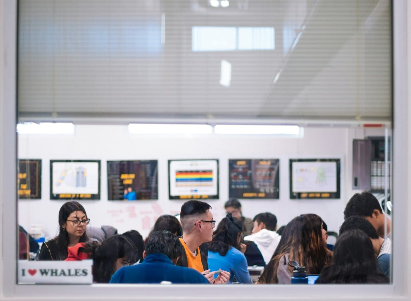 Studenten arbeiten an einem Tisch in einem hellen, modernen Raum zusammen.